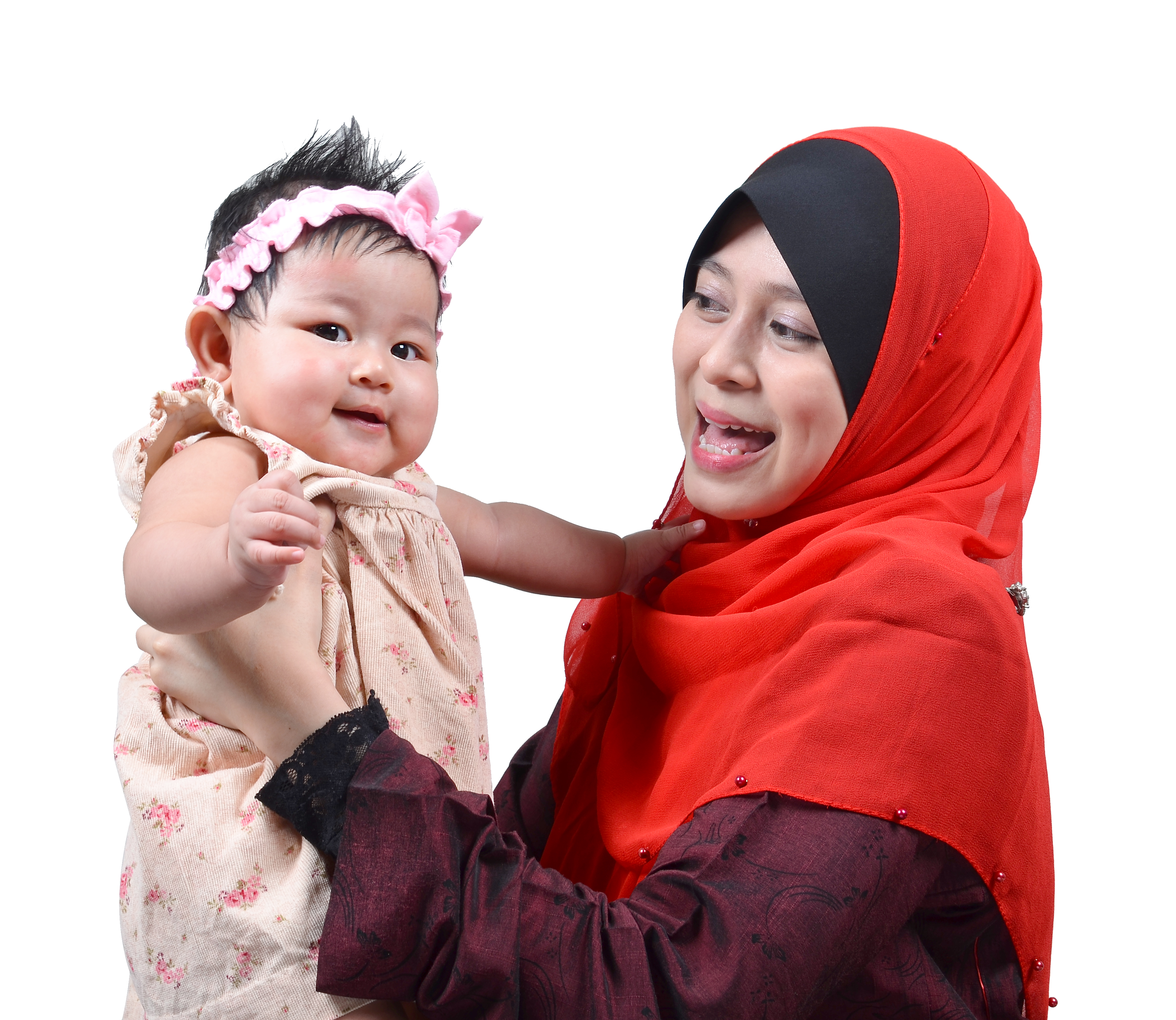 mother wearing red hijab lifts up smiling baby in pink